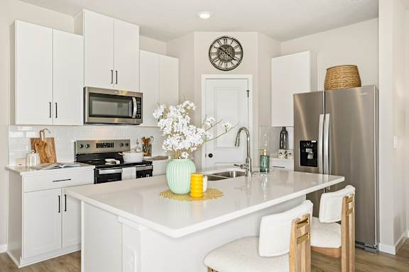 A white kitchen with a clock on the wall.