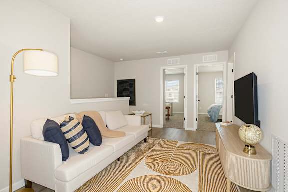 A living room with a white couch and a gold floor lamp.