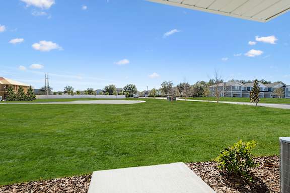 A large grassy field with a few buildings in the distance.