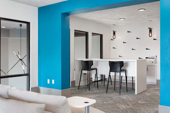 A modern living room with a white couch and a blue accent wall.
