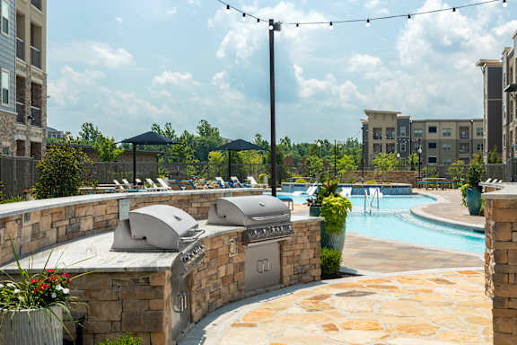 A pool area with a hot tub and a barbecue grill.