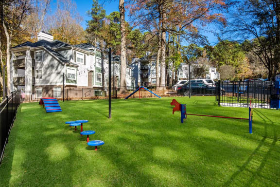 a grassy area with a playground and houses in the background