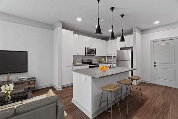 A modern kitchen with a grey sofa and a white island.