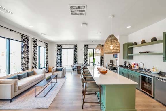 A modern kitchen and living room with a long island in the middle.