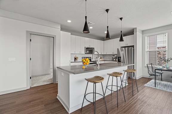 A modern kitchen with a bar stool and a dining table.