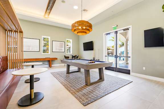 A living room with a pool table and a television.
