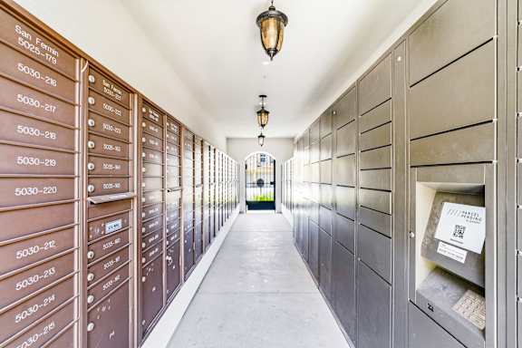 A long hallway with mailboxes on the wall and a light hanging from the ceiling.