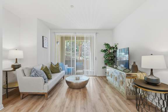 A living room with a white sofa, a coffee table, and a lamp.