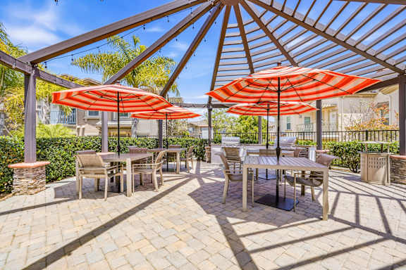 A patio with tables and chairs under umbrellas.