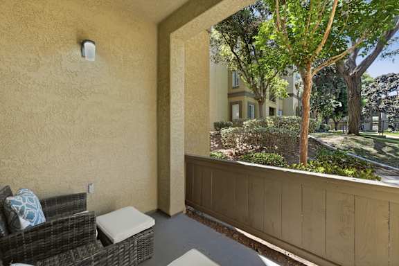 A balcony with a wicker chair and a pillow.