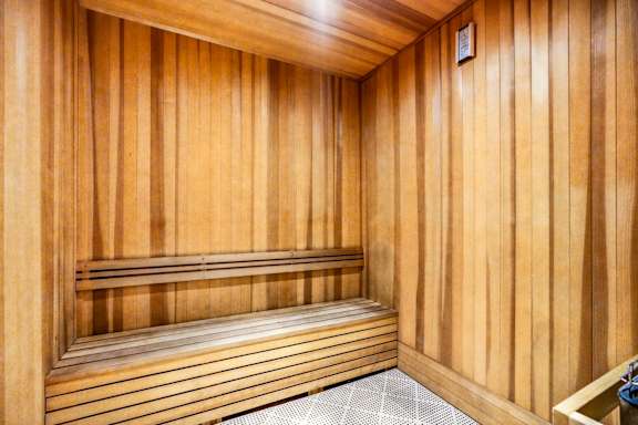 A wooden sauna with a bench and a door.