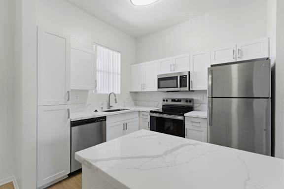 A kitchen with white cabinets and appliances.