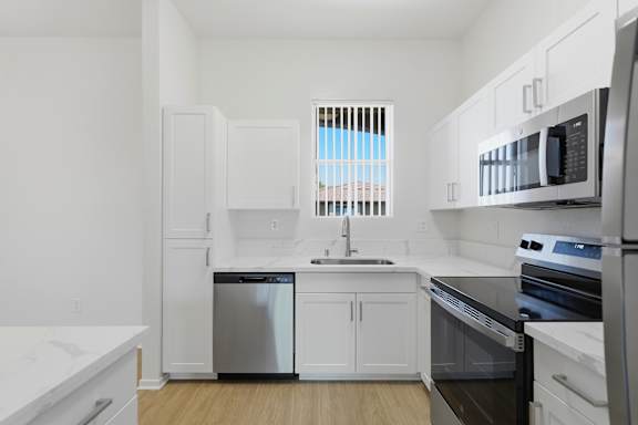 A kitchen with white cabinets and black appliances.