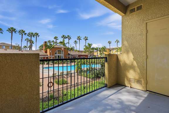 A balcony with a pool and palm trees in the background.