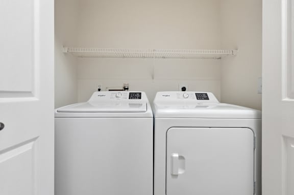 Two white front loading washing machines in a small laundry room.
