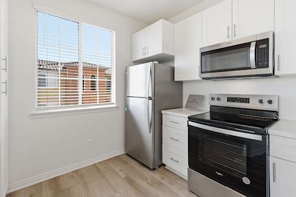A kitchen with a stainless steel refrigerator, oven, and microwave.