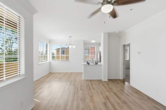 A room with a ceiling fan and wooden flooring.