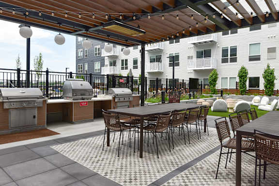 A patio with a table and chairs and a grill.