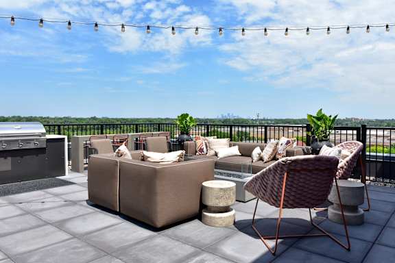 A patio with a couch, chair, and table with a view of the water.