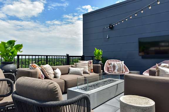 A patio with a couch, chairs, and a table with a glass top.