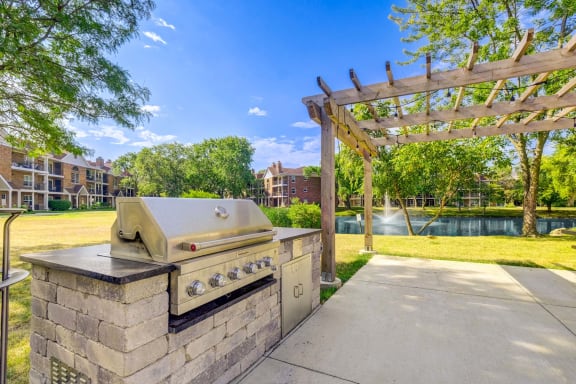 an outdoor kitchen with a grill and a pergola