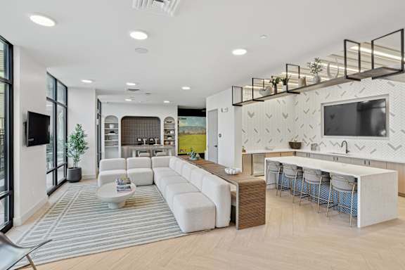 A modern living room with a white sofa set and a television on the wall.