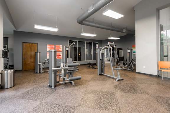 A gym with a variety of equipment including treadmills, weights, and exercise machines.