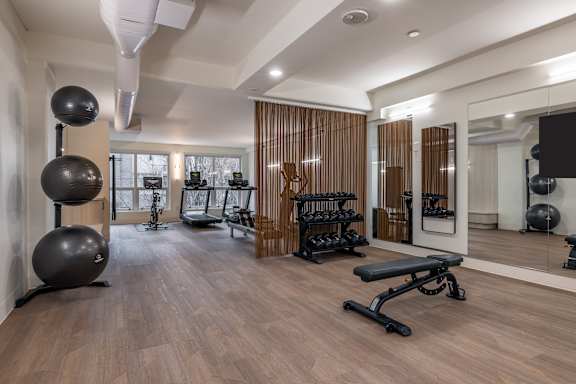 A spacious home gym with wooden floors and a variety of exercise equipment.