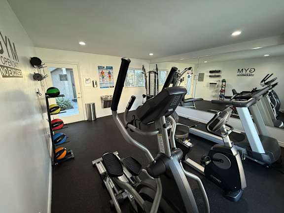 A gym with a variety of exercise equipment including treadmills, stationary bikes, and weight machines.