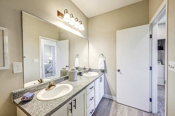 A bathroom with a double sink vanity and a mirror above it.