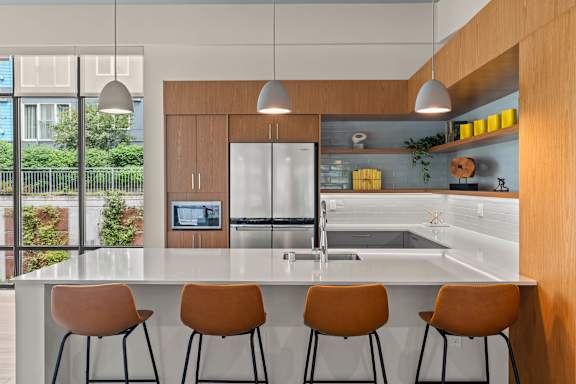 A modern kitchen with a white countertop and orange chairs.