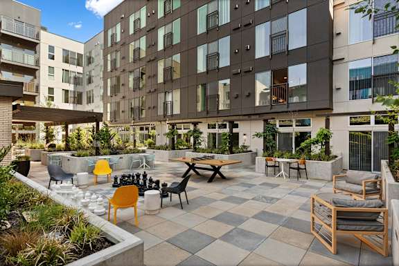 A courtyard with a checkerboard patterned floor and a variety of chairs and tables.