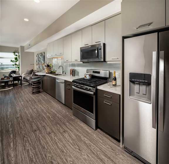 A modern kitchen with stainless steel appliances and wooden flooring.
