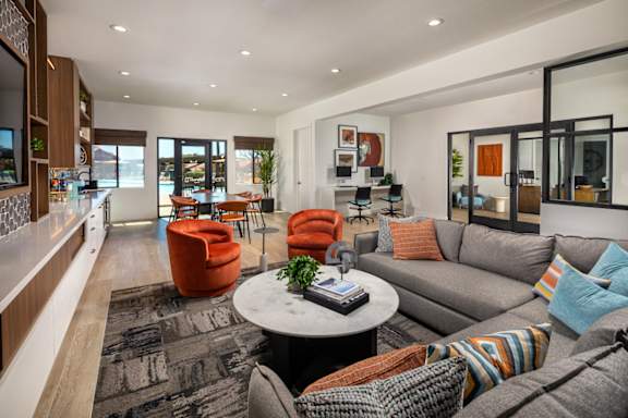 A modern living room with a grey sofa and orange chairs.