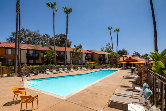 Swimming pool with chairs and trees and buildings in the background at Bella Terra, 92081