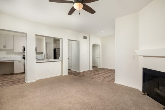 an empty living room with a fireplace and a ceiling fan