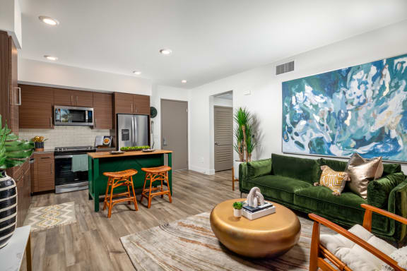 a living room with a green couch and wooden stools at Citron, Anaheim