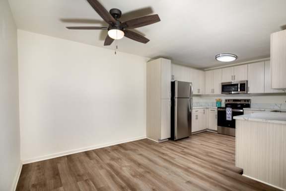 A kitchen with a refrigerator, microwave, and oven.