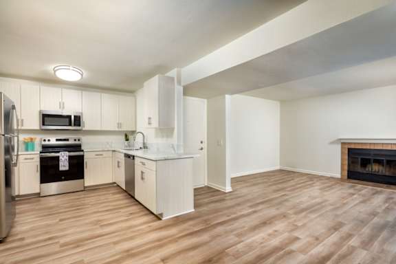 A kitchen with white cabinets and a wood floor.