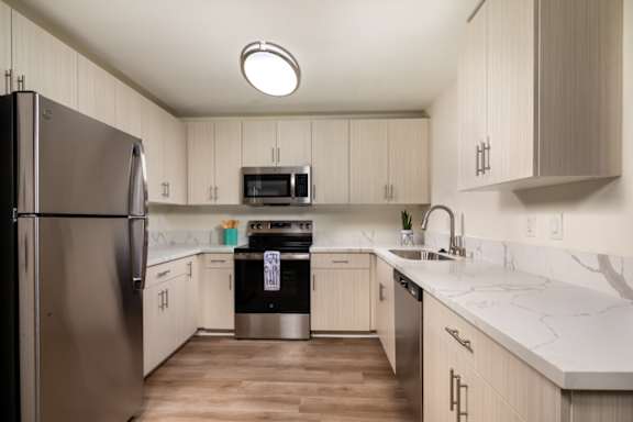 A kitchen with a stainless steel refrigerator and wooden cabinets.
