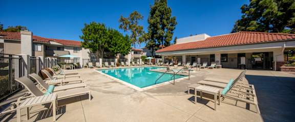 A swimming pool surrounded by lounge chairs and trees.