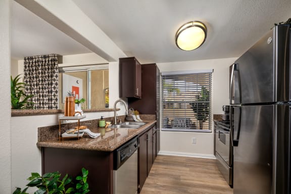 Redesigned kitchen with stainless steel appliances and granite counter tops and a window at Tuscany Ridge, Temecula