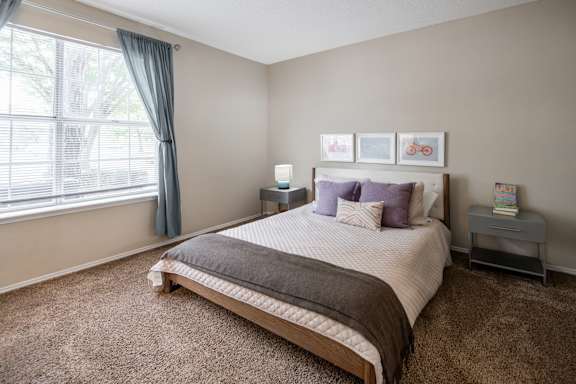 A bedroom with a large bed and a window with curtains.