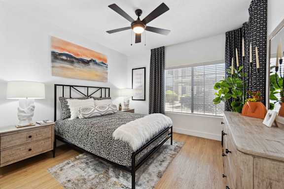 A bedroom with a bed, dresser, and ceiling fan.