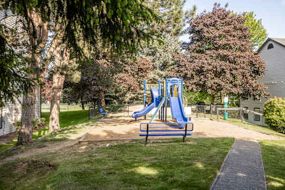 A playground with a blue slide and a bench.