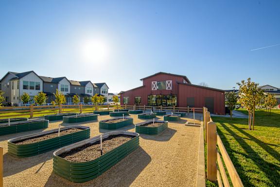 A sunny day at a farm with a red barn and green raised garden beds. at The Orchard Townhomes, Sandy, Utah