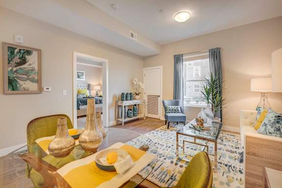 A living room with a yellow table and a blue and white rug.