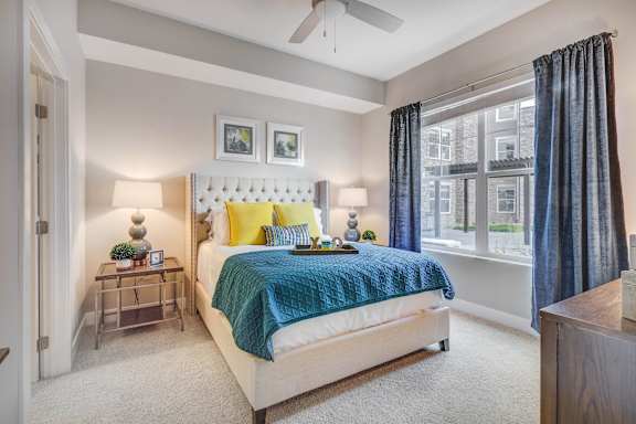A bedroom with a bed, nightstands, and a window.
