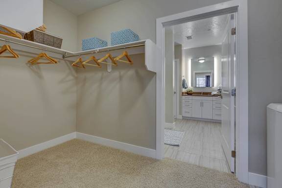 A room with a carpeted floor and a closet with clothes hanging.