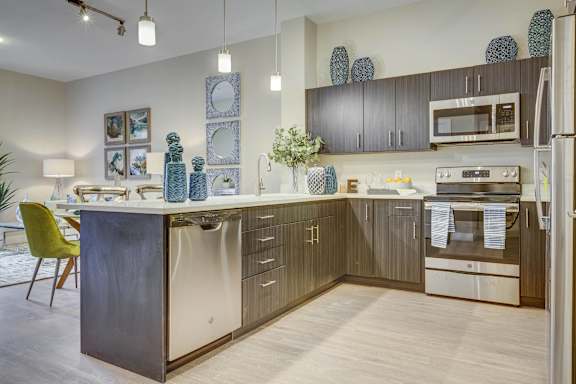 A modern kitchen with a wooden floor and a green chair.